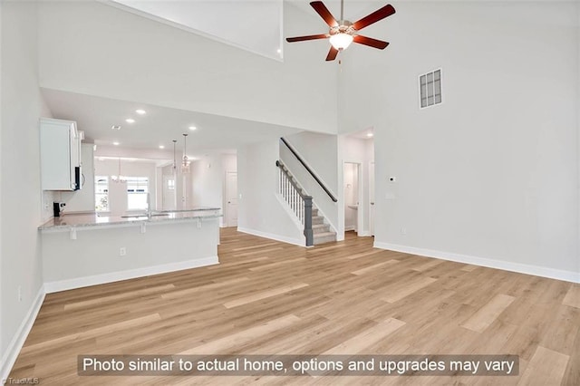 unfurnished living room with visible vents, stairway, baseboards, and light wood-style floors