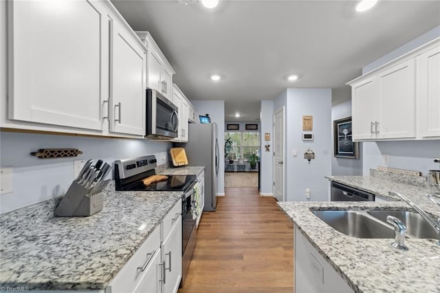 kitchen featuring stainless steel appliances, wood finished floors, a sink, and white cabinets