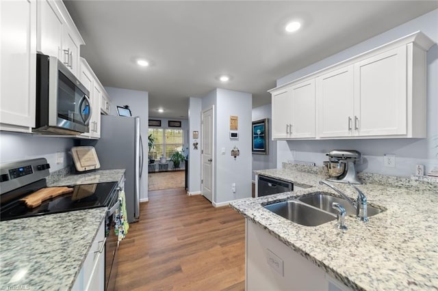 kitchen featuring dark wood finished floors, stainless steel appliances, recessed lighting, white cabinetry, and a sink