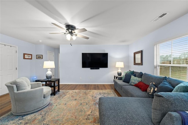 living room with baseboards, visible vents, ceiling fan, and wood finished floors