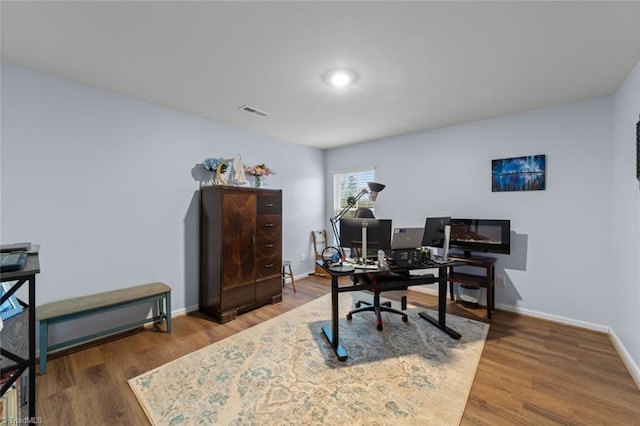 home office with wood finished floors, visible vents, and baseboards