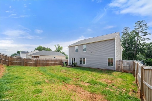 rear view of house featuring a fenced backyard and a yard