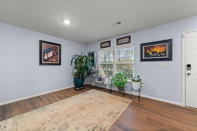 living area with baseboards, visible vents, and wood finished floors