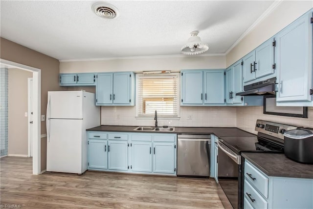 kitchen with dark countertops, stainless steel appliances, blue cabinetry, and under cabinet range hood