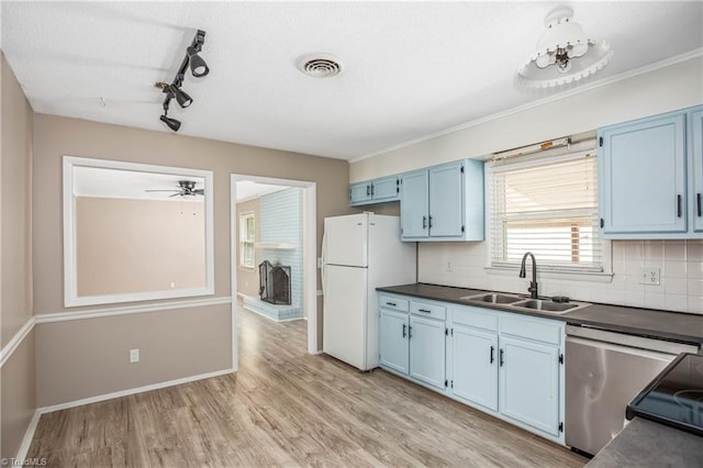 kitchen featuring dark countertops, a sink, blue cabinetry, freestanding refrigerator, and stainless steel dishwasher