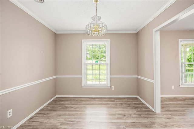 empty room featuring an inviting chandelier, crown molding, wood finished floors, and a wealth of natural light