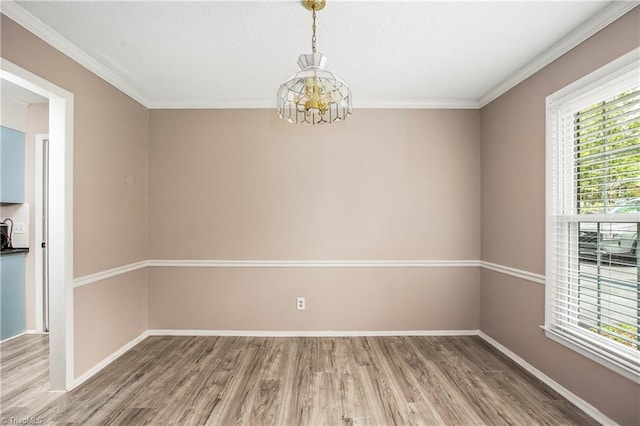 empty room featuring a chandelier, a healthy amount of sunlight, and wood finished floors