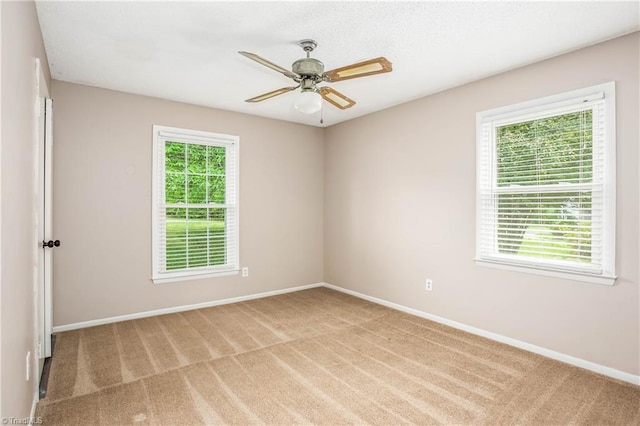 carpeted empty room featuring baseboards and ceiling fan