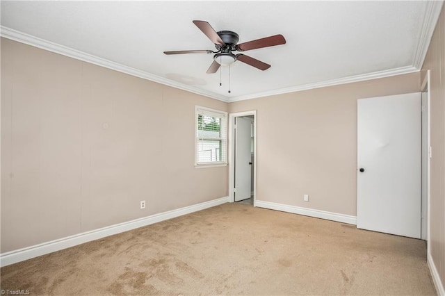 carpeted empty room with baseboards, ornamental molding, and a ceiling fan