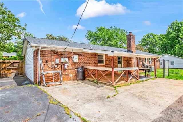 back of house with fence, a chimney, and brick siding