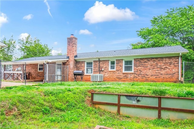 rear view of house featuring brick siding, fence, a chimney, and central AC unit