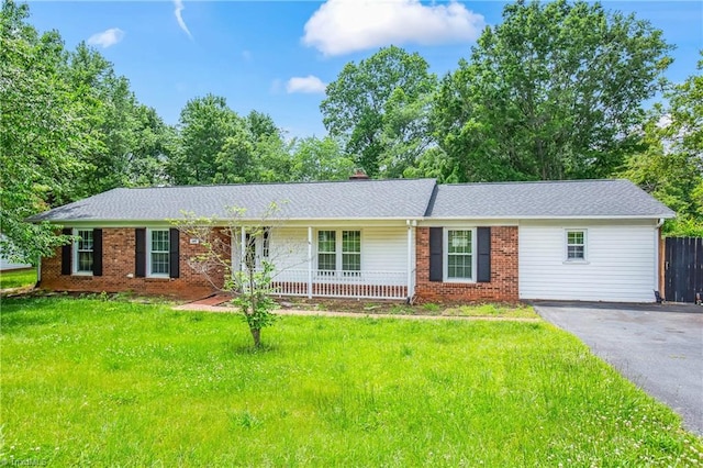 ranch-style home with covered porch, brick siding, a front lawn, and aphalt driveway