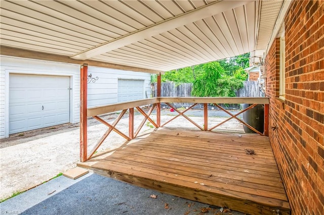 wooden terrace featuring fence and a garage