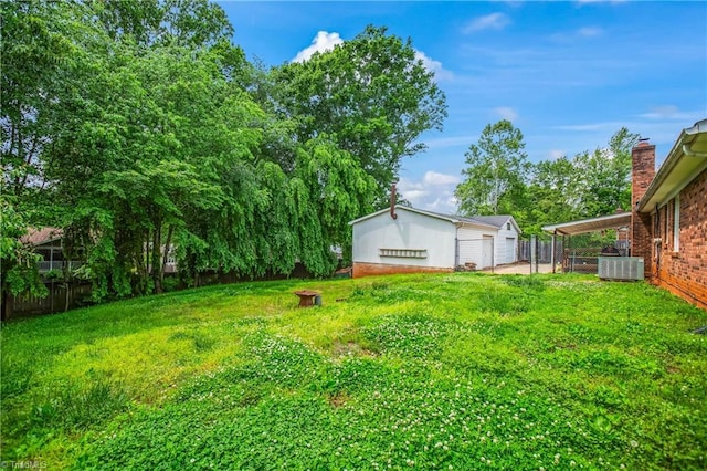 view of yard with central AC, fence, an outbuilding, and a garage