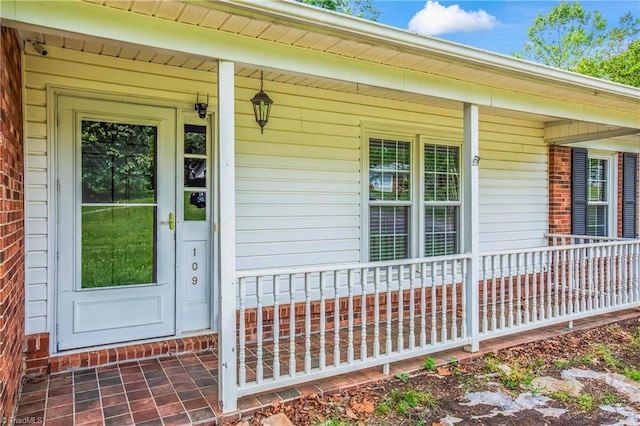 property entrance featuring a porch and brick siding