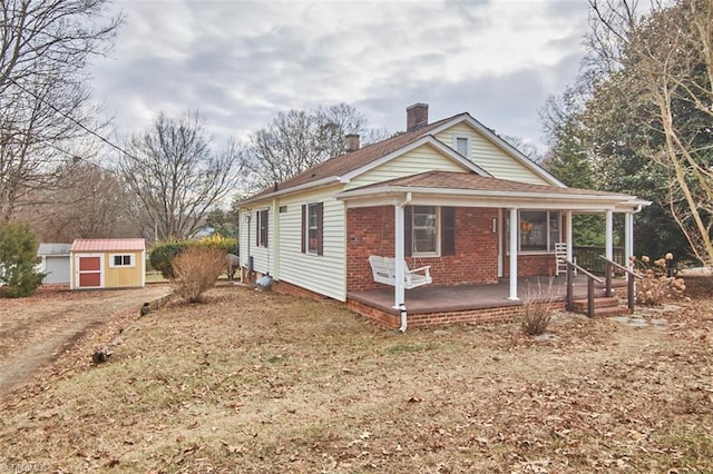 view of front of property featuring a porch and a storage shed