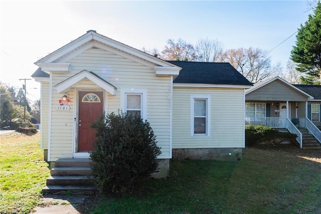 bungalow-style home featuring covered porch and a front yard