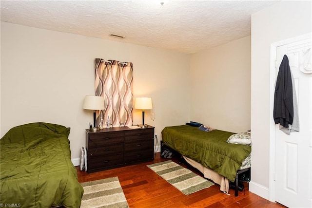 bedroom with dark wood-type flooring and a textured ceiling