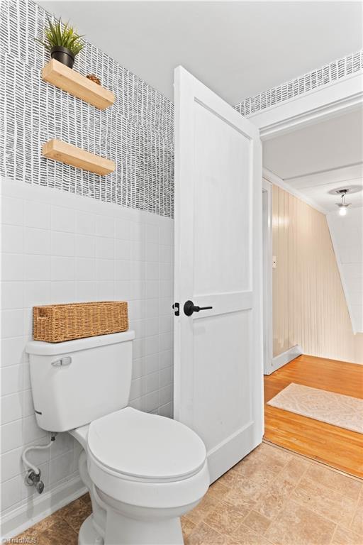 bathroom with toilet and tile walls