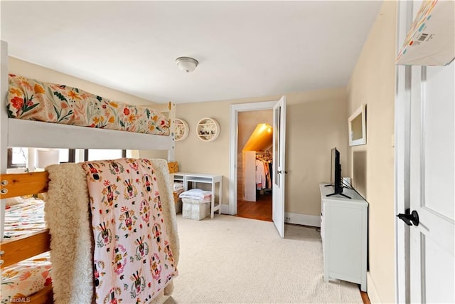 bedroom with light colored carpet, a walk in closet, and a closet