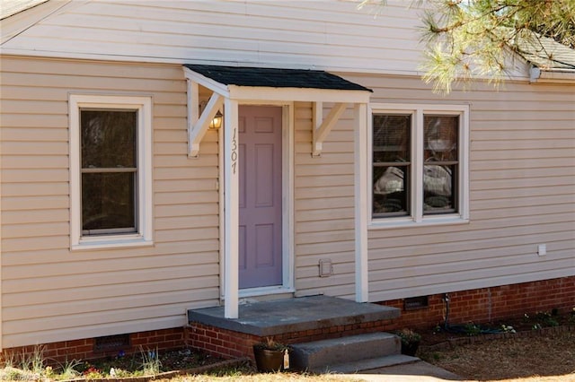 view of exterior entry with crawl space and roof with shingles