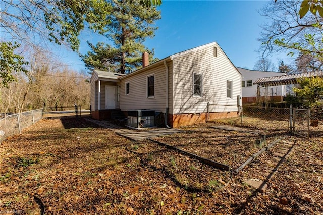 rear view of house featuring entry steps, a fenced backyard, central AC, crawl space, and a chimney