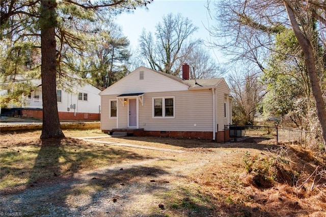 view of front of home featuring crawl space, a chimney, and fence