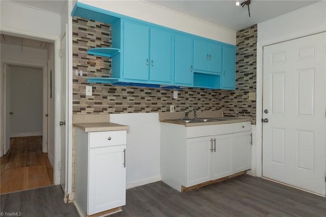 kitchen with open shelves, tasteful backsplash, light countertops, dark wood-type flooring, and a sink