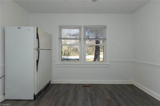 unfurnished dining area featuring dark wood-type flooring, visible vents, and baseboards