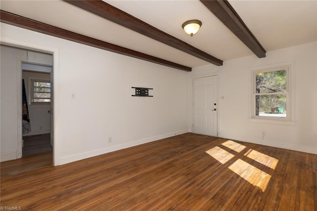 unfurnished room featuring dark wood finished floors, beam ceiling, and baseboards