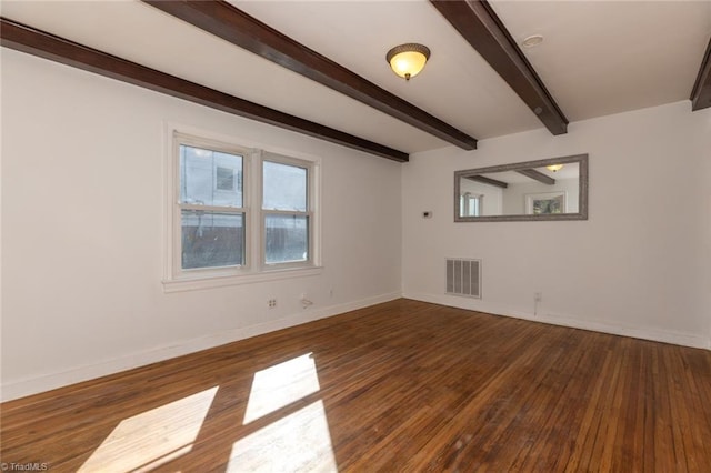 spare room featuring visible vents, beamed ceiling, baseboards, and wood finished floors