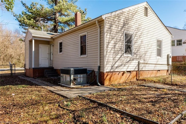 back of property with a chimney, central AC unit, entry steps, crawl space, and fence