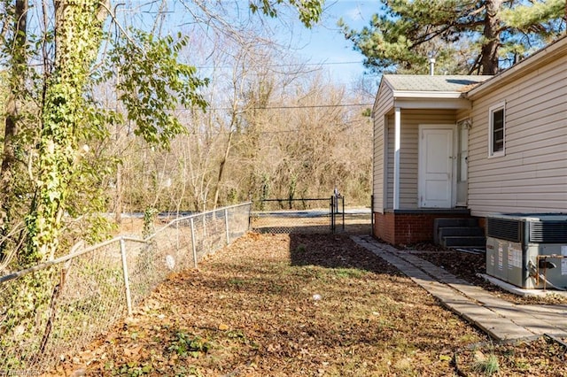 view of yard with central AC unit, fence, and a gate