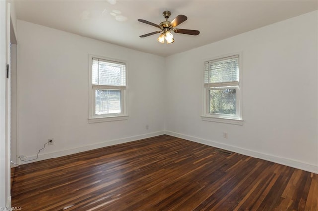 spare room with visible vents, dark wood-style flooring, a ceiling fan, and baseboards