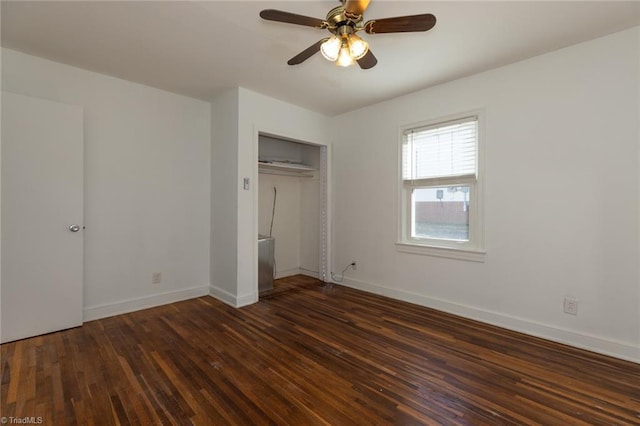 unfurnished bedroom with dark wood-type flooring, a closet, baseboards, and a ceiling fan