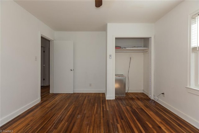 unfurnished bedroom featuring baseboards, dark wood finished floors, and a closet