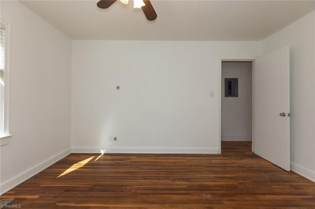 empty room with electric panel, ceiling fan, baseboards, and wood finished floors