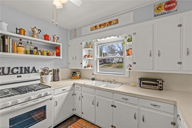 kitchen featuring white gas stove, open shelves, light countertops, white cabinetry, and a sink