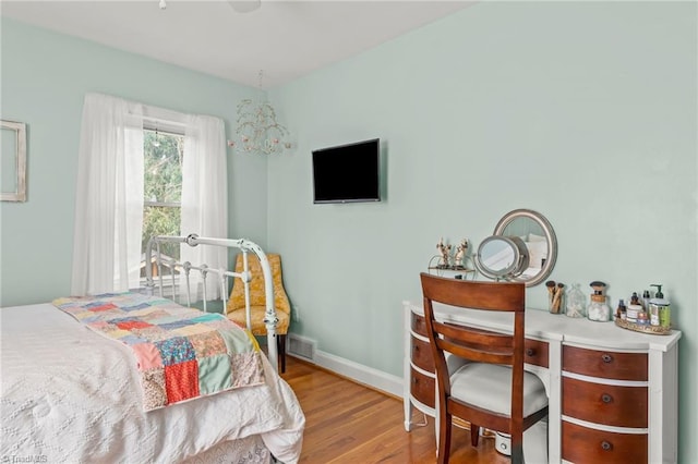 bedroom with visible vents, baseboards, and wood finished floors