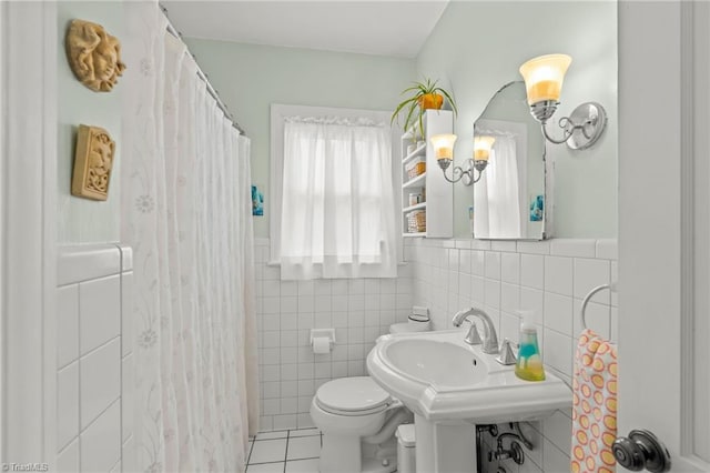 bathroom with a sink, tile walls, toilet, and tile patterned floors