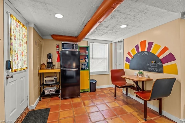 kitchen with recessed lighting, stainless steel microwave, freestanding refrigerator, a textured ceiling, and baseboards