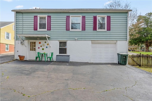 view of front of property featuring a garage, fence, driveway, and stucco siding