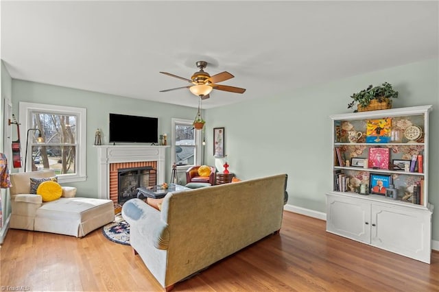 living room featuring ceiling fan, a fireplace, plenty of natural light, and wood finished floors