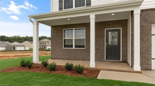 view of exterior entry with a yard and covered porch