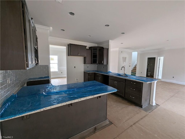 kitchen with light stone counters, a peninsula, a sink, dark brown cabinetry, and tasteful backsplash