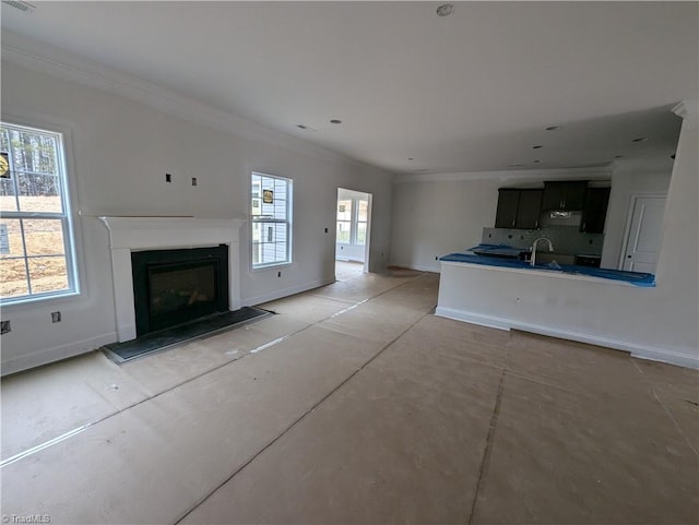 unfurnished living room featuring a sink, baseboards, a glass covered fireplace, and crown molding