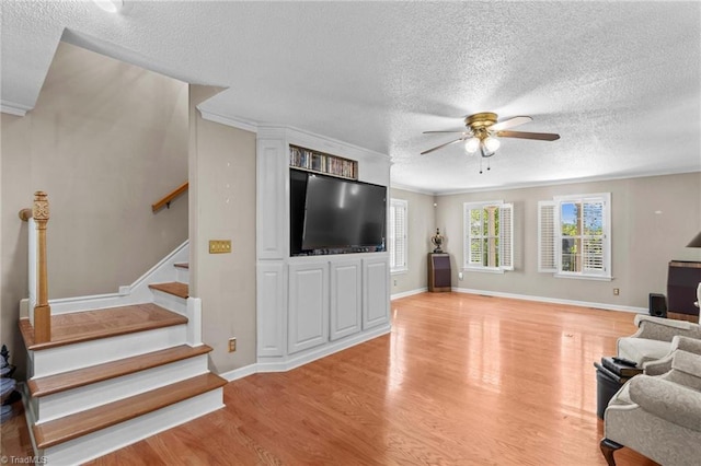 422 Wildwood Dr, Salisbury, NC 28146 - living room featuring light wood-style flooring, a textured ceiling, a ceiling fan, stairway, and ornamental molding