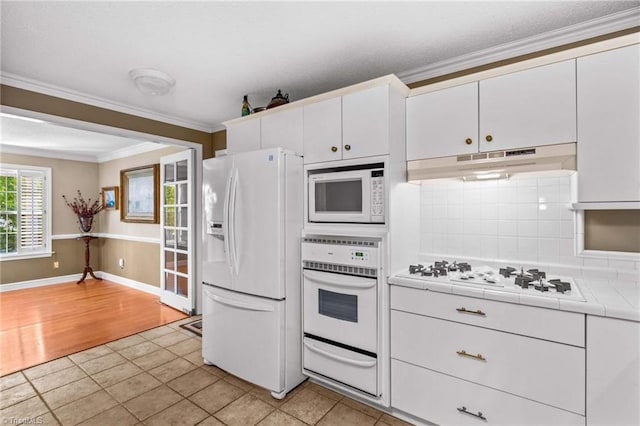 422 Wildwood Dr, Salisbury, NC 28146 - kitchen featuring tile counters, under cabinet range hood, ornamental molding, white appliances, and a warming drawer