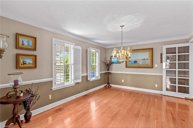 422 Wildwood Dr, Salisbury, NC 28146 - unfurnished dining area with a textured ceiling, baseboards, a notable chandelier, wood finished floors, and ornamental molding