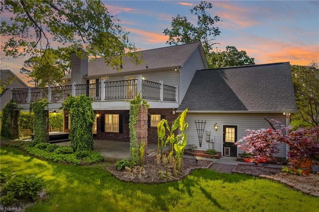 422 Wildwood Dr, Salisbury, NC 28146 - back of property at dusk with a balcony, a chimney, a yard, a patio, and roof with shingles